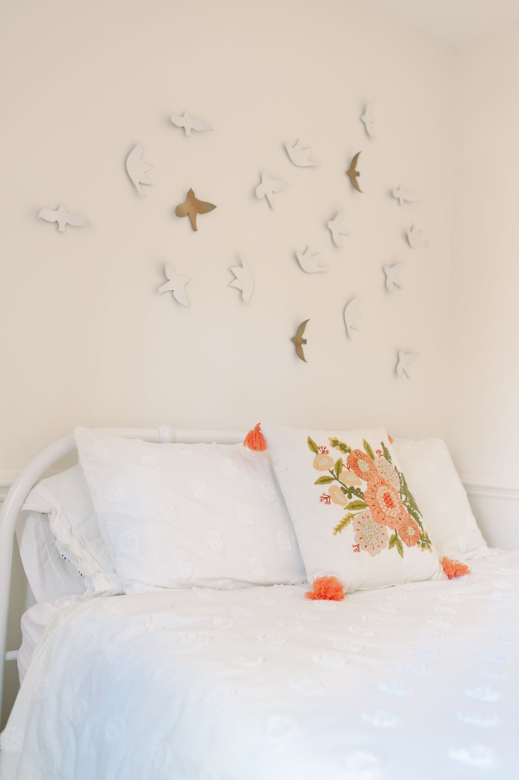 Little Girl's Room showing bed with white metal headboard, white comforter, floral pillow, and bird art